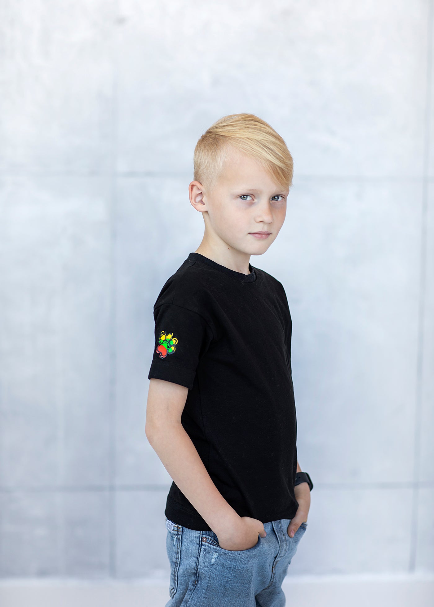 Berniukas stovi apsirengęs juodus laisvalaikio marškinėlius
