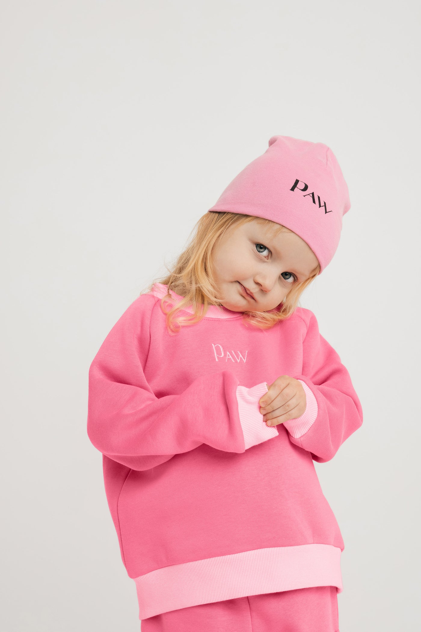 Mergaitė su rožine kepure ir džemperiu