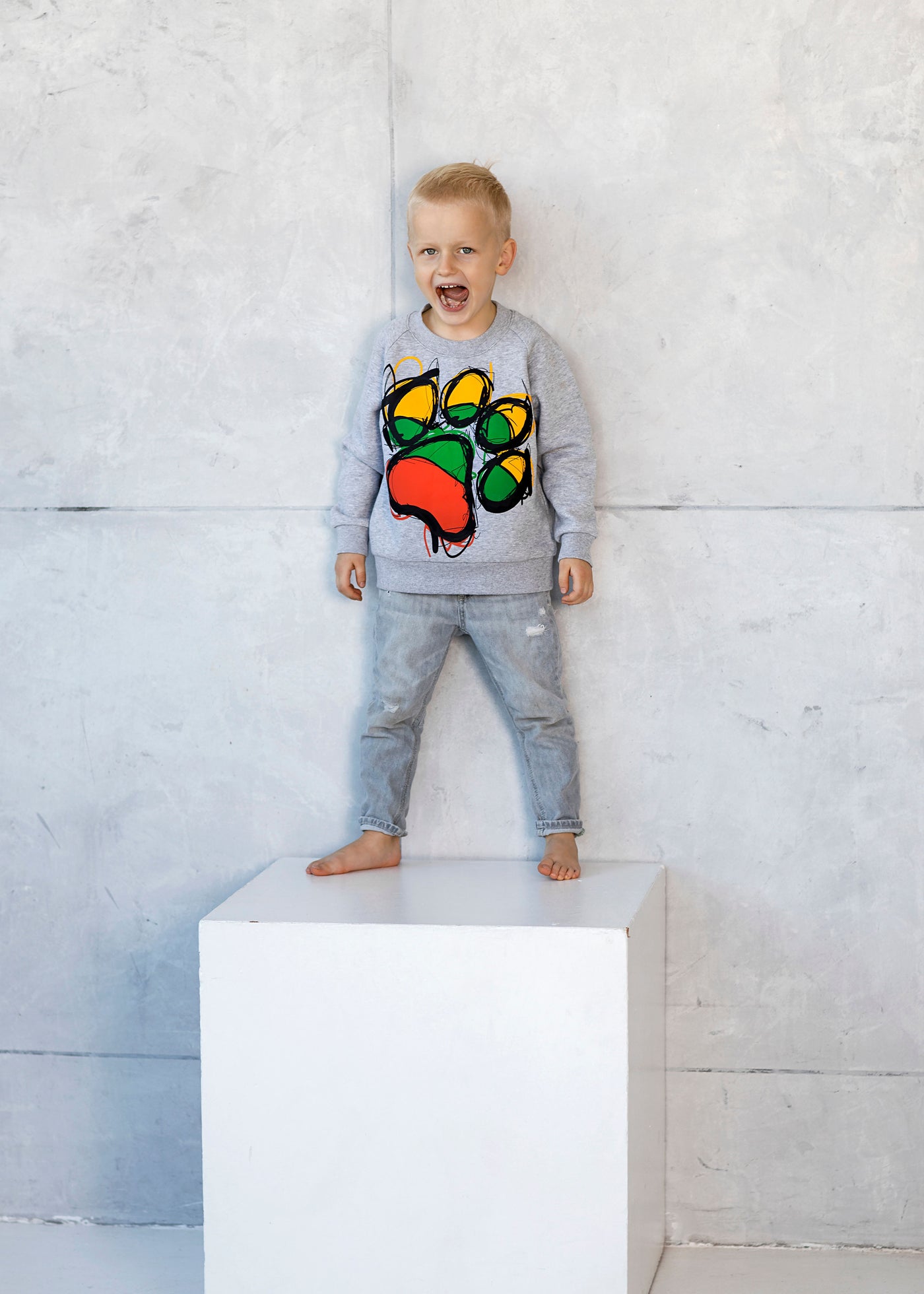 Berniukas su vaikišku džemperiu pilkos spalvos su trispalvės pėdutėmis